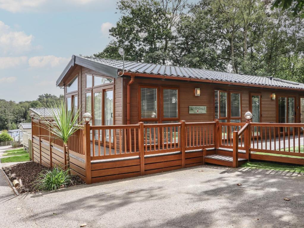 a large wooden cabin with a large deck at The Rivendale in St. Leonards