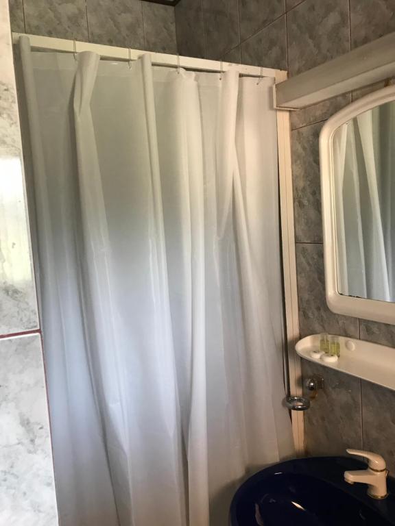 La salle de bains est pourvue d'une douche avec rideau de douche blanc. dans l'établissement Casa postolache, à Soveja