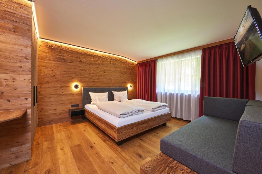 1 dormitorio con 1 cama, TV y sofá en Appartements Christiane Knöpfle en Oberammergau