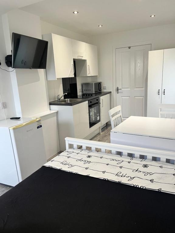 a kitchen with white cabinets and a bed in a room at Modern Comfy One Bed Apartment - Free Parking in Glasgow