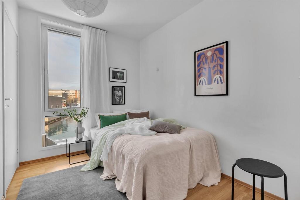 a white bedroom with a bed and a window at Seaside city appartment in Tromsø