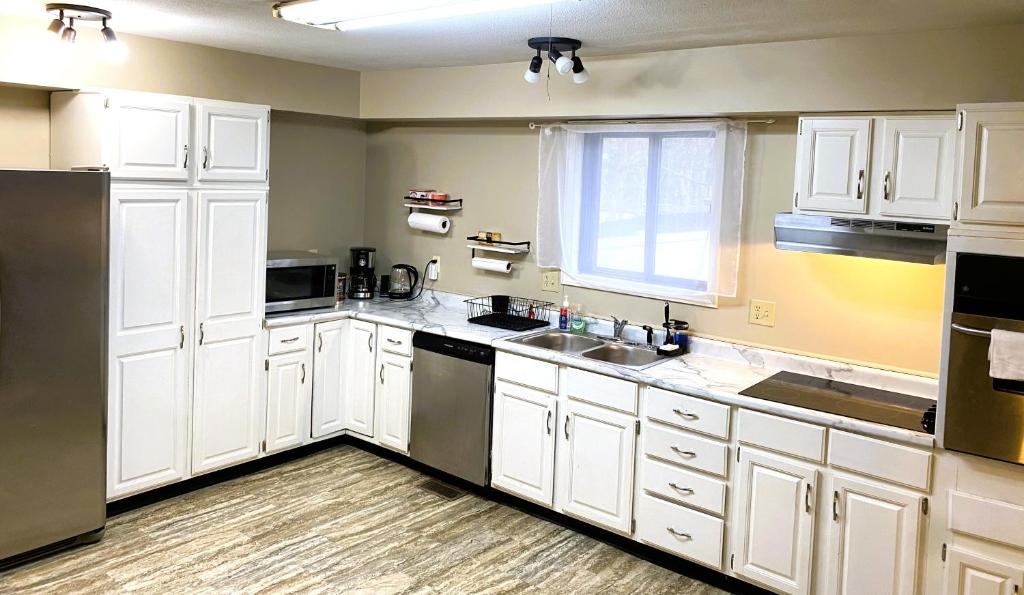 a kitchen with white cabinets and a sink and a window at Spanish Style 3-bedroom Home with Hot Tub in Indianapolis