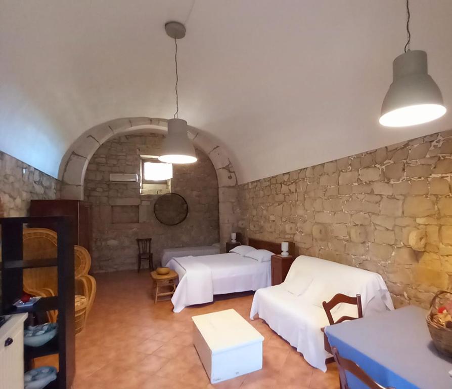 a room with two beds and a stone wall at Liolà in Modica