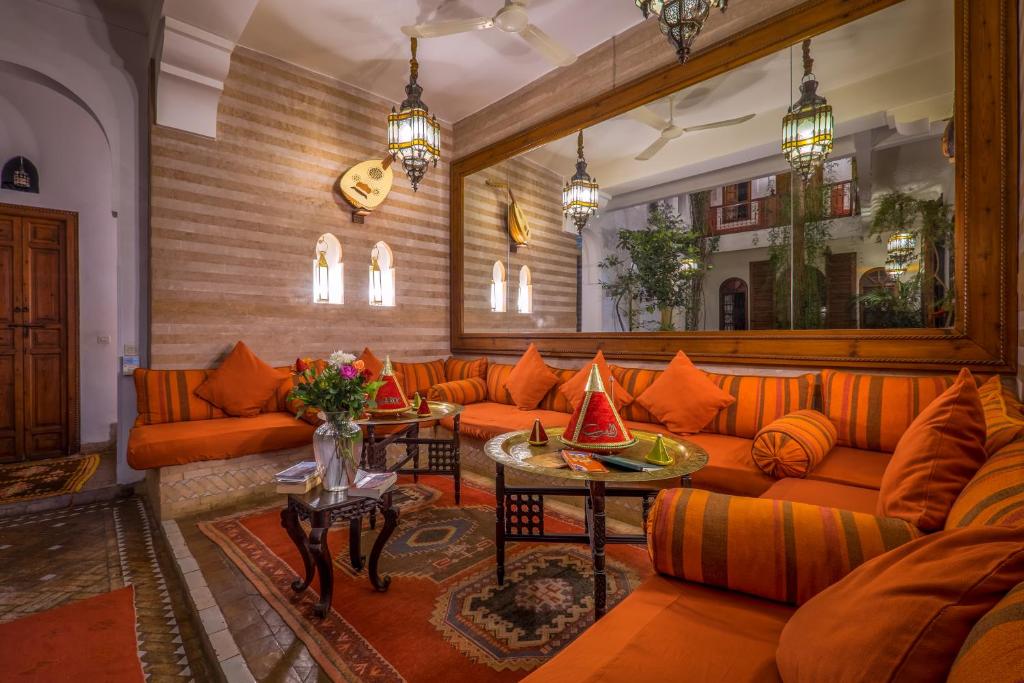 a living room with orange couches and a table at Riad Sable Chaud in Marrakesh