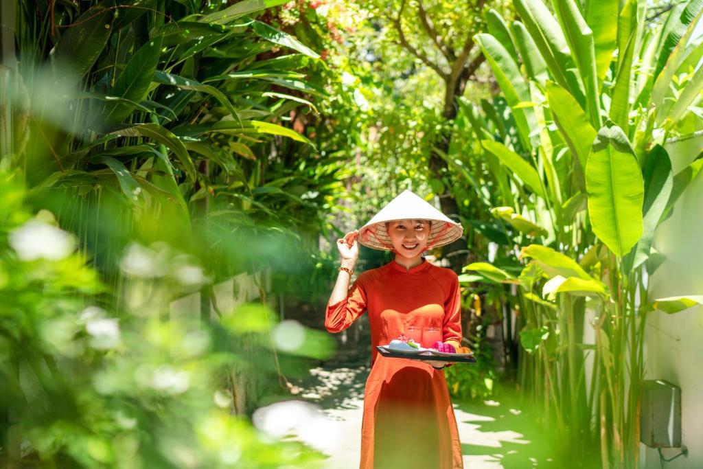 uma mulher de chapéu a andar pela floresta em December Hoi An Villa em Hoi An