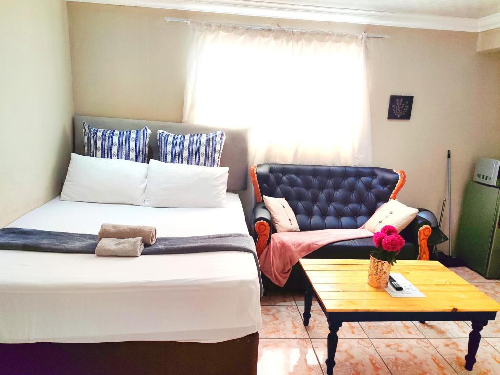 um quarto com uma cama, uma cadeira e uma mesa em Zikora em Pretoria