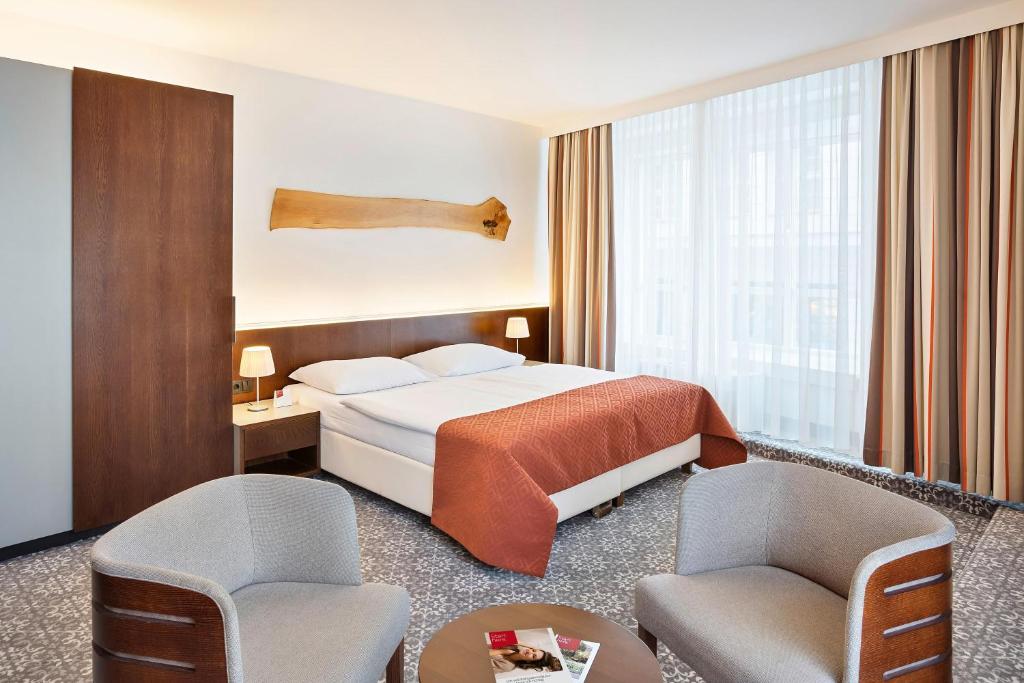 um quarto de hotel com uma cama e duas cadeiras em Austria Trend Hotel Europa Wien em Viena