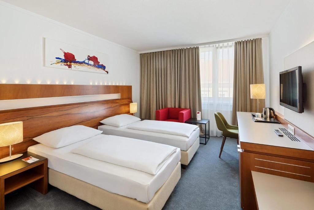 um quarto de hotel com duas camas e uma secretária em Austria Trend Hotel Europa Graz Hauptbahnhof em Graz