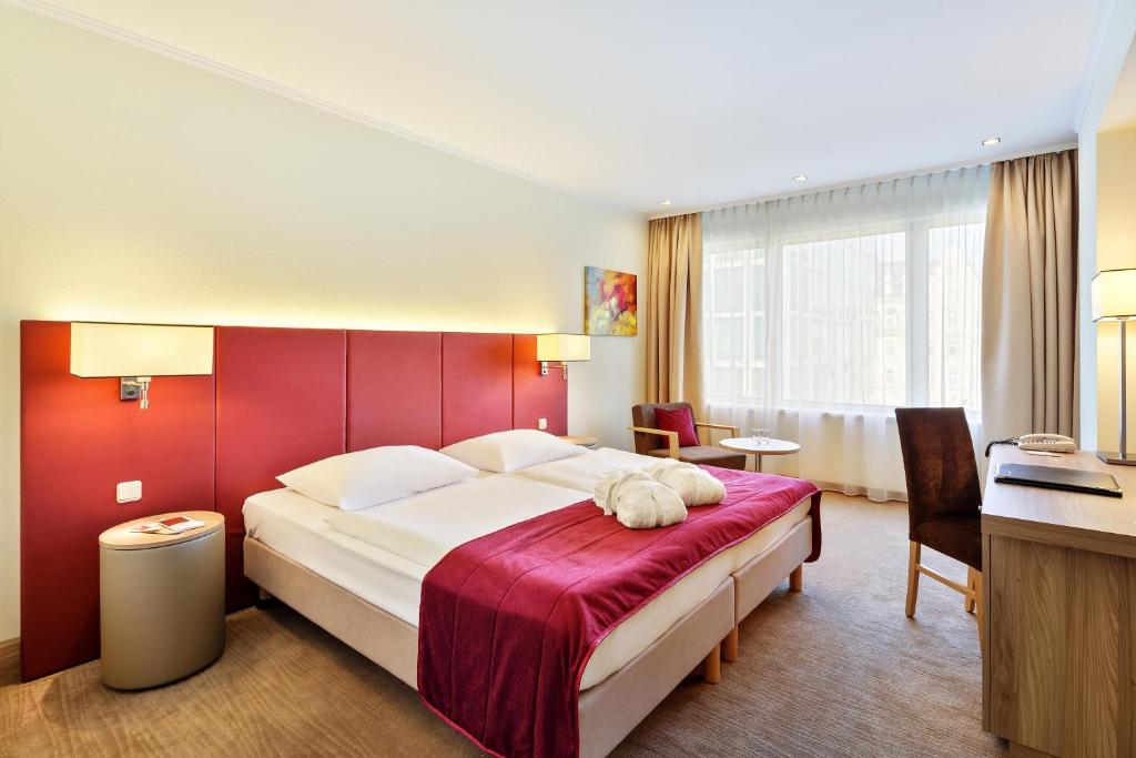 a bedroom with a large bed with a red wall at Hotel Schillerpark Linz, a member of Radisson Individuals in Linz