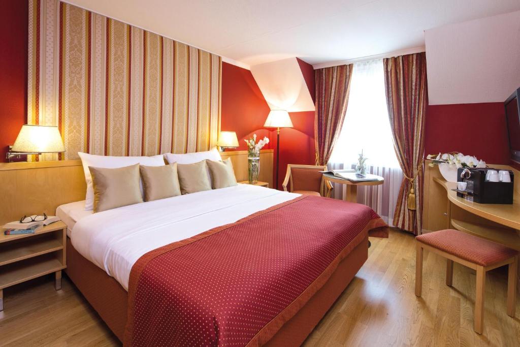 a hotel room with a large bed and a desk at Austria Trend Hotel Ananas Wien in Vienna
