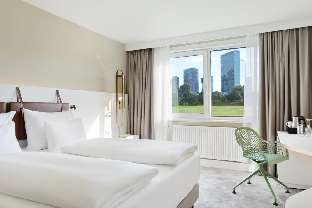 a hotel room with two beds and a desk and a window at Austria Trend Hotel Bosei Wien in Vienna