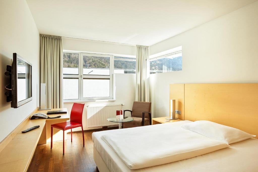 a bedroom with a bed and a desk and a table at Austria Trend Hotel Congress Innsbruck in Innsbruck