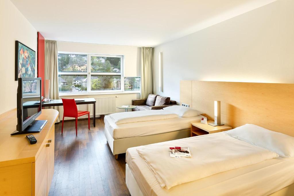 a hotel room with two beds and a desk at Austria Trend Hotel Congress Innsbruck in Innsbruck