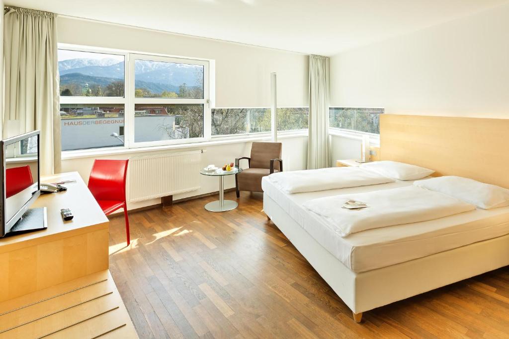 a hotel room with a bed and a desk and window at Austria Trend Hotel Congress Innsbruck in Innsbruck