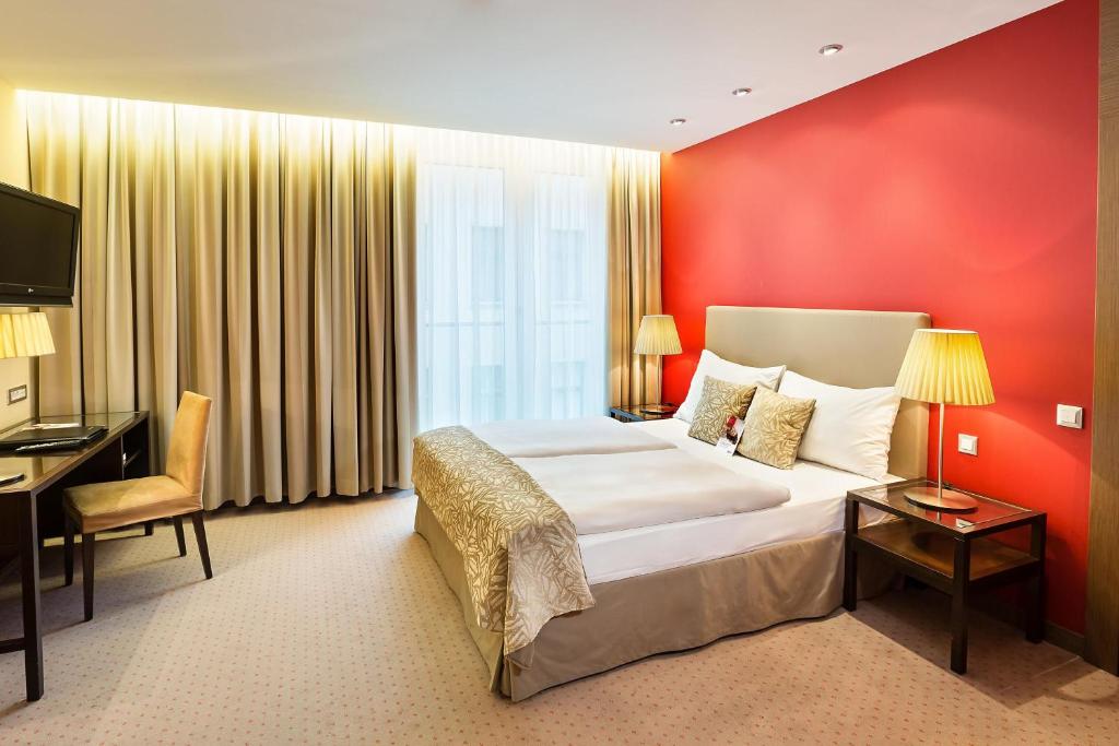 a hotel room with a large bed and a desk at Austria Trend Hotel Savoyen Vienna - 4 stars superior in Vienna