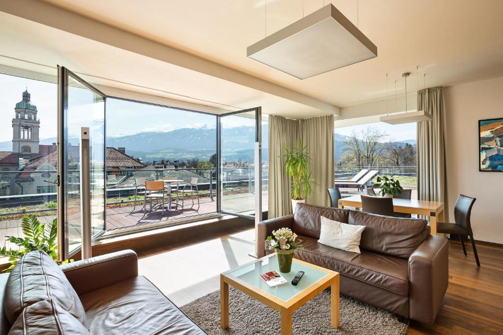 a living room with a couch and a large window at Austria Trend Hotel Congress Innsbruck in Innsbruck