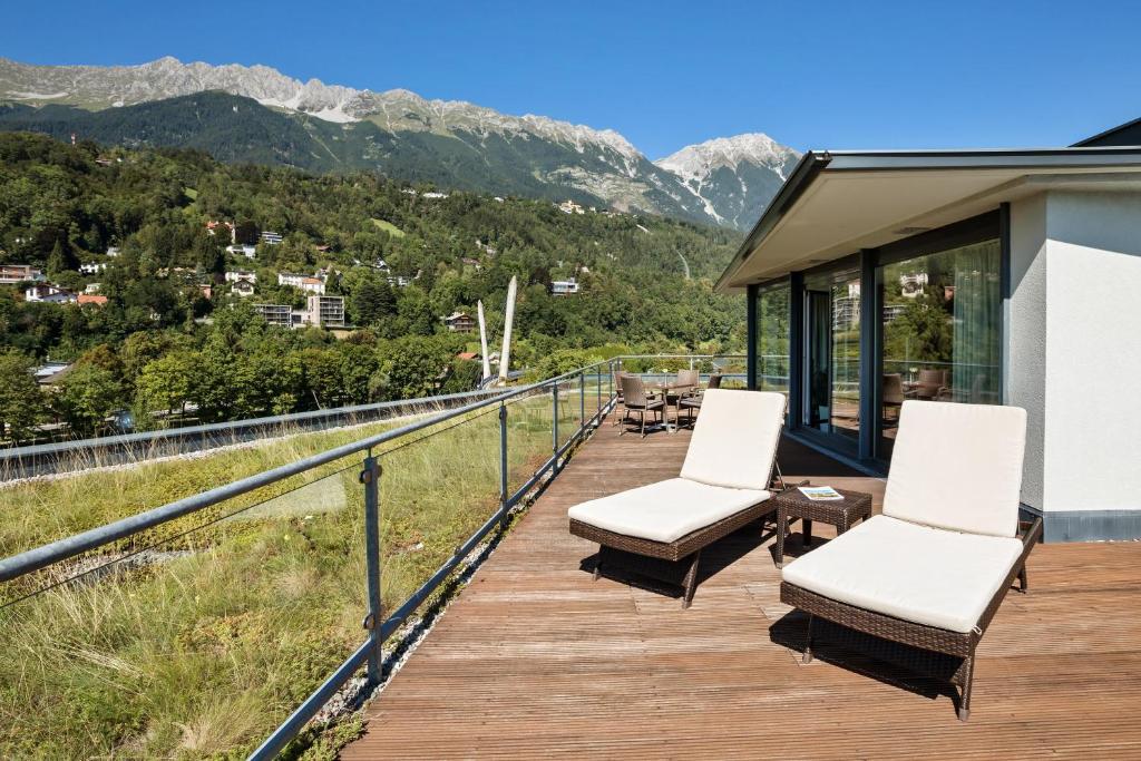 a deck with chairs and tables and mountains at Austria Trend Hotel Congress Innsbruck in Innsbruck