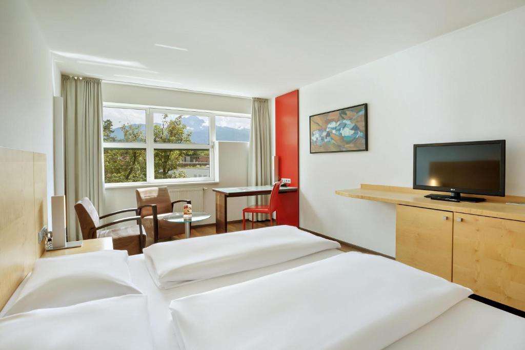a hotel room with two beds and a flat screen tv at Austria Trend Hotel Congress Innsbruck in Innsbruck