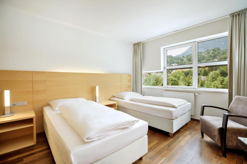 a hotel room with two beds and a window at Austria Trend Hotel Congress Innsbruck in Innsbruck