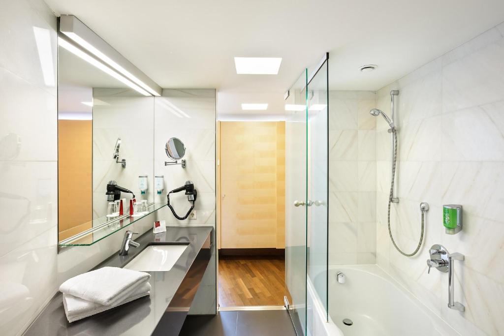 a bathroom with a shower and a sink and a tub at Austria Trend Hotel Congress Innsbruck in Innsbruck