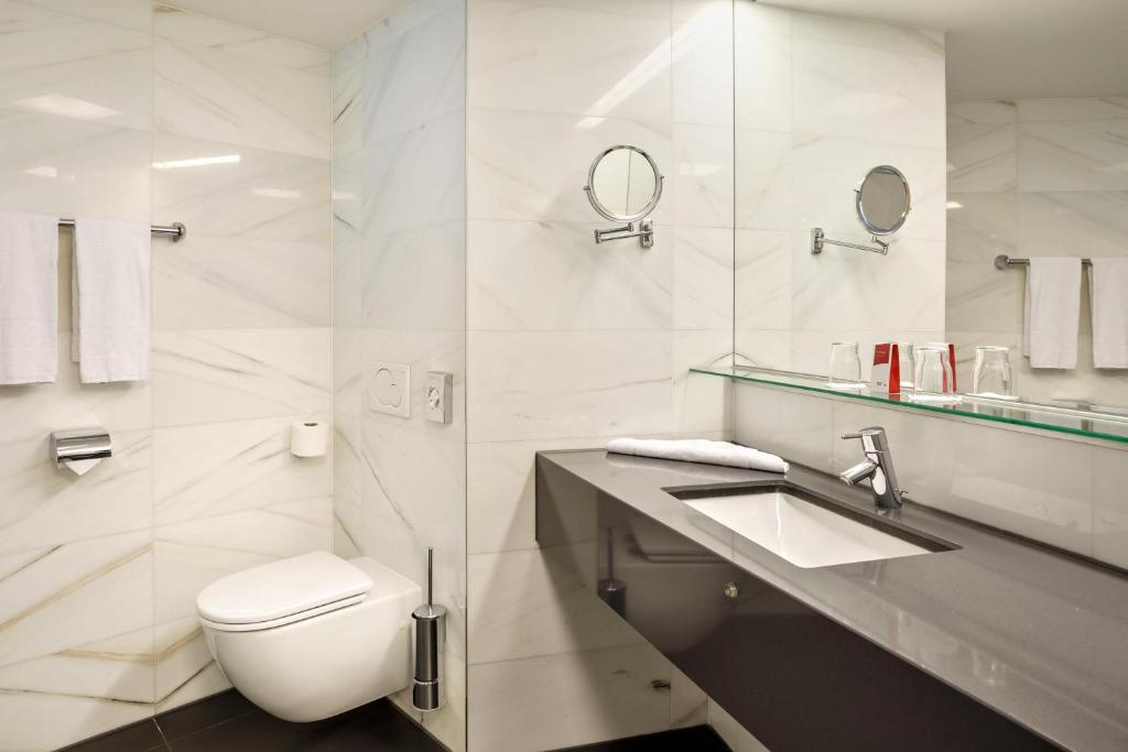 a white bathroom with a toilet and a sink at Austria Trend Hotel Congress Innsbruck in Innsbruck