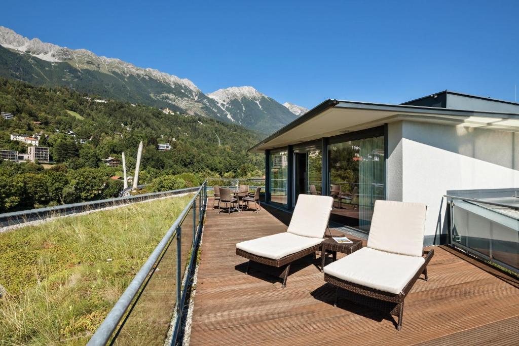 a balcony of a house with white chairs and mountains at Austria Trend Hotel Congress Innsbruck in Innsbruck