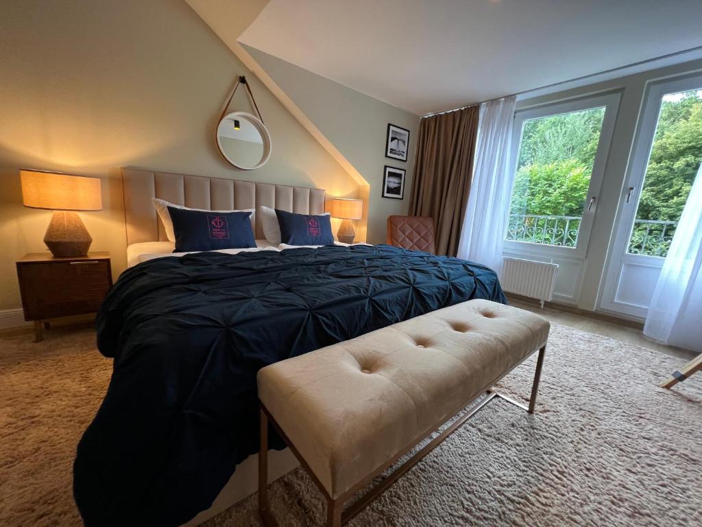 a bedroom with a bed with a black blanket and a bench at Hafen Hotel Schützenhof in Burg auf Fehmarn