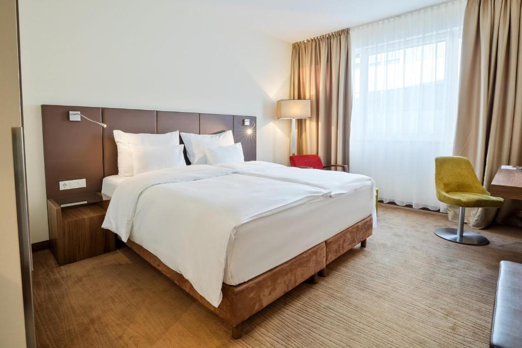 ein Hotelzimmer mit einem großen Bett und einem Stuhl in der Unterkunft Austria Trend Hotel Doppio Wien in Wien
