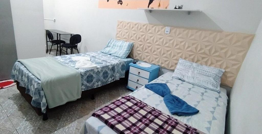 a bedroom with two beds and a table at Acomodações no Jardim Tropical em Rondonópolis in Rondonópolis