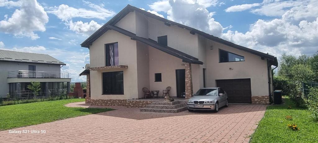 Biały dom z samochodem zaparkowanym przed nim w obiekcie Vila Catalina w mieście Baia Mare