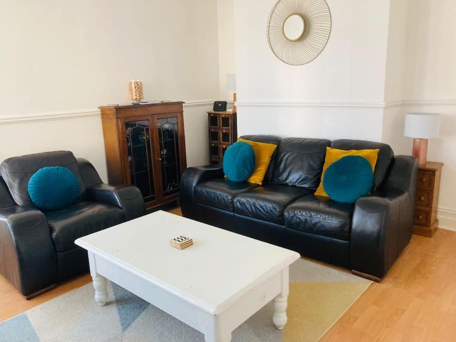 a living room with a black leather couch and a coffee table at No.18 - Ground Floor apartment close to the beach in Cromer