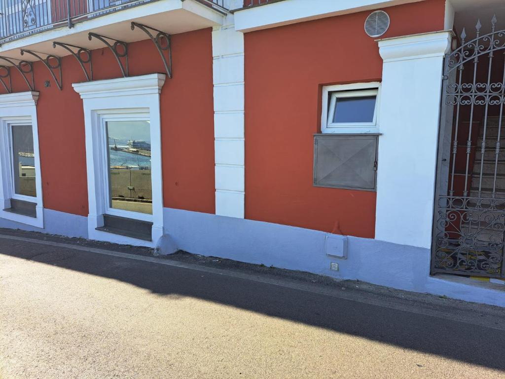 un edificio rosso e bianco con finestre e cancello di Tre Re Appartamento Matima a Capri