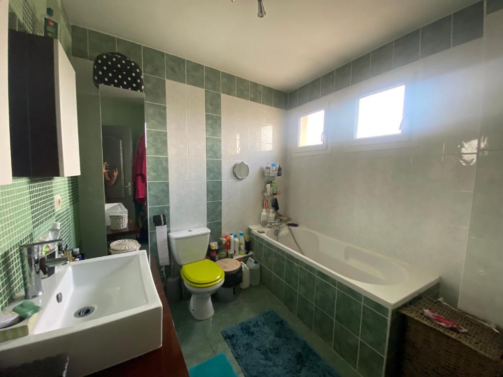 a bathroom with a tub and a toilet and a sink at Agréables chambres dans maison suspendue in Saint-Étienne