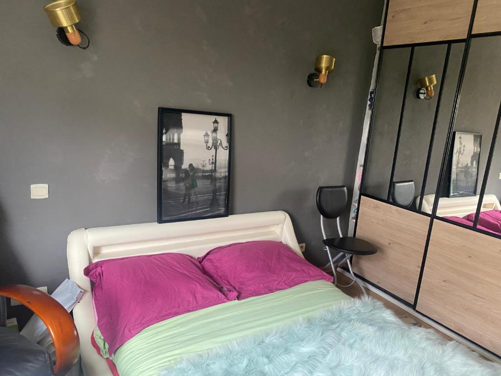 a bedroom with a bed with pink and green sheets at Agréables chambres dans maison suspendue in Saint-Étienne