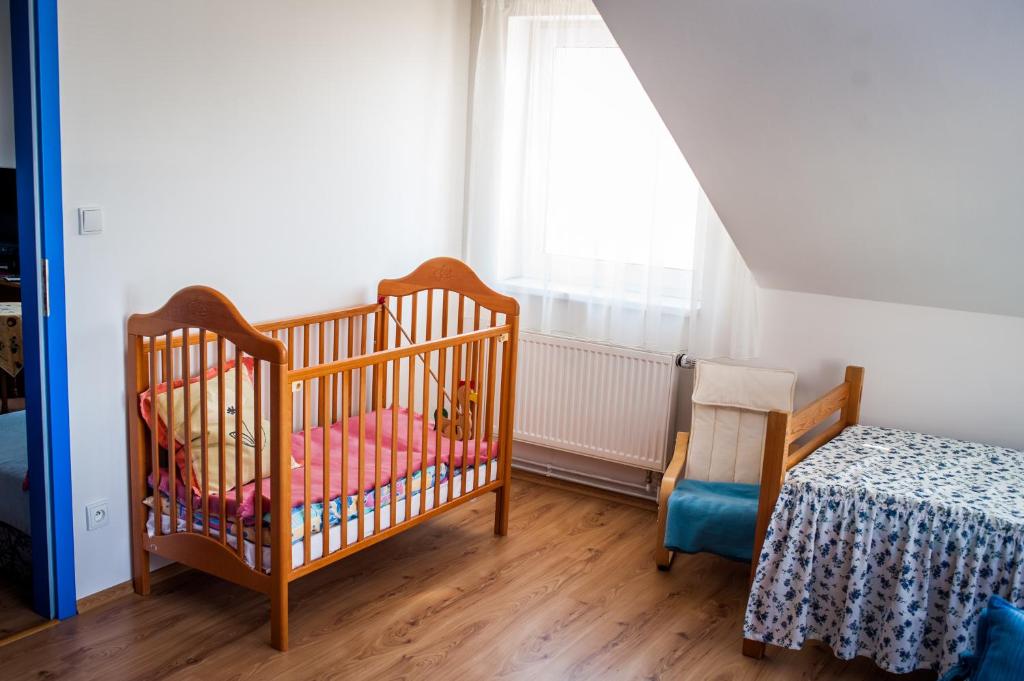 Pokój z 2 łóżeczkami dziecięcymi, stołem i oknem w obiekcie Apartmány Batelov w mieście Batelov