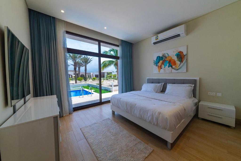 um quarto com uma cama e uma grande janela com uma piscina em Palm House em Salalah