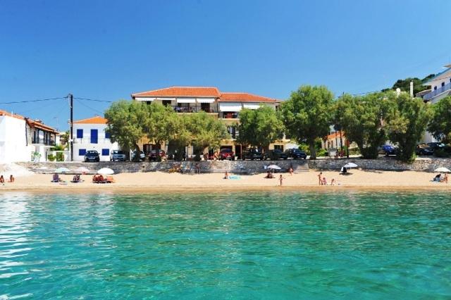 a beach with people and umbrellas in the water at Hotel Korakakis Beach in Finikounta