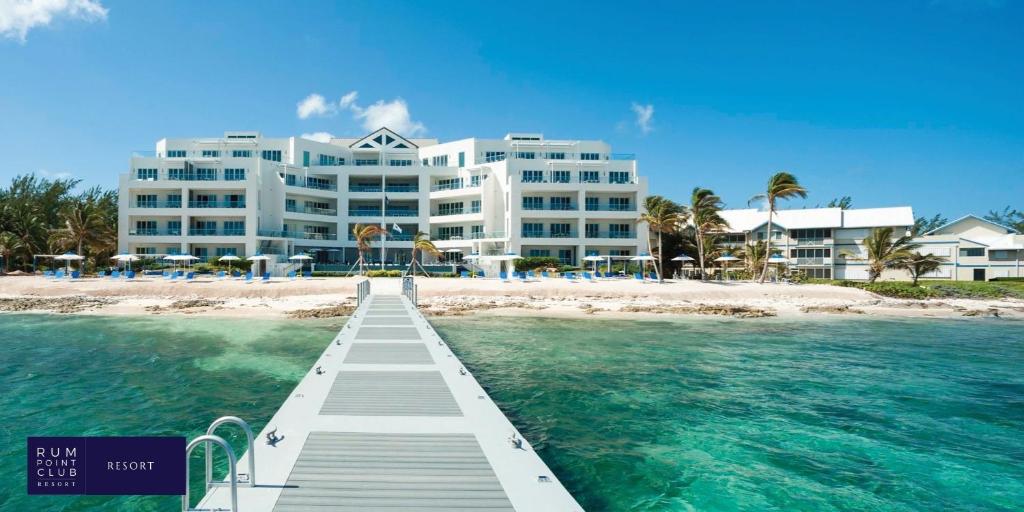 a building on the beach with a dock in the water at Rum Point Club Resort Luxury Beachfront Condos by Grand Cayman Villas & Condos in Driftwood Village