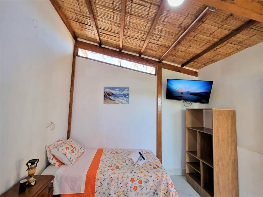 1 dormitorio con 1 cama y TV en la pared en Bright Bungalow 3 -Close to Ocean, en Zorritos
