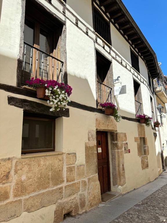 a building with flowers on the windows and a door at Hotel Rural Princesa Kristina in Covarrubias