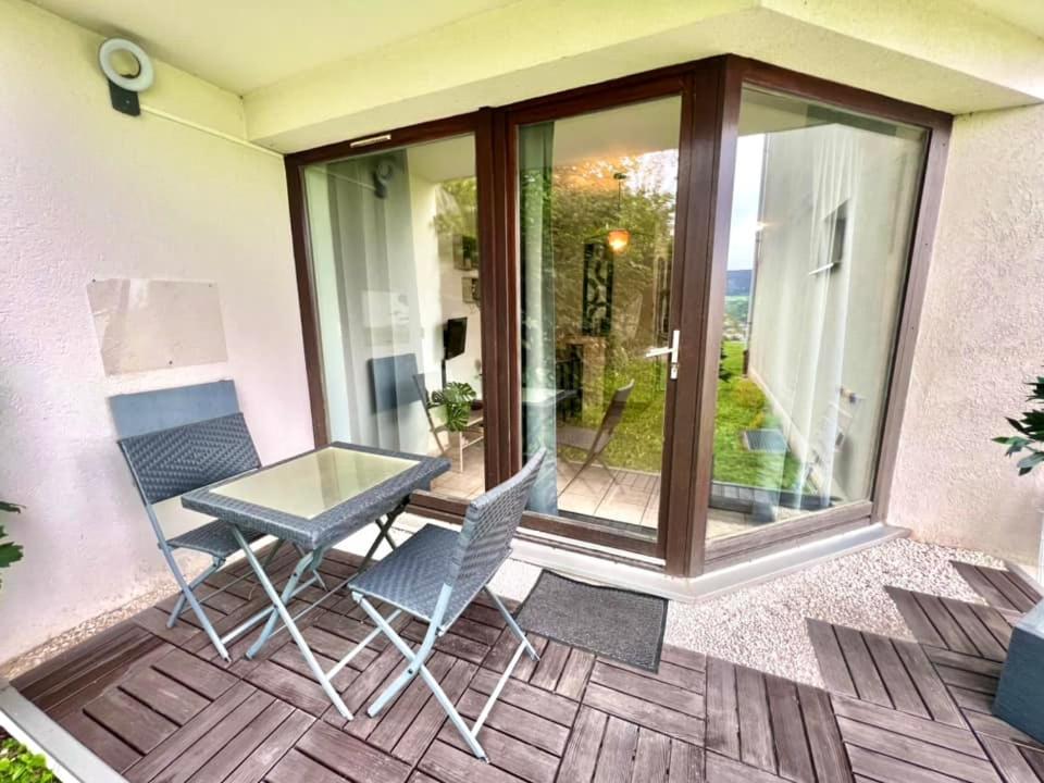 a patio with a glass table and two chairs at Joli studio cosy, vue magnifique et terrasse privée in Gérardmer