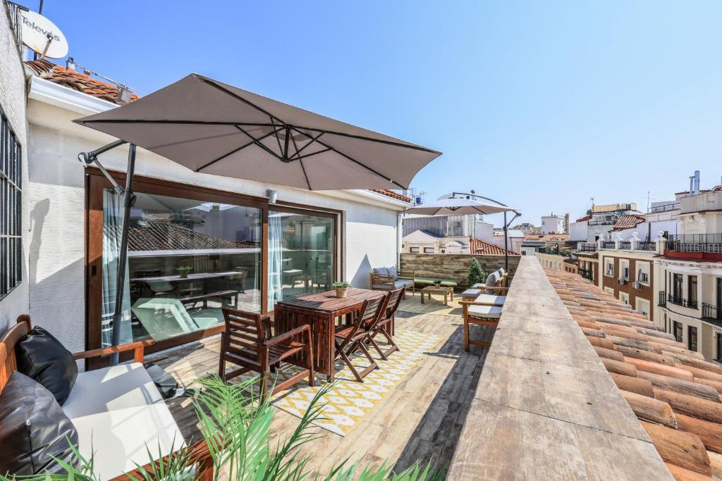 een patio met een tafel en een parasol op een dak bij Atico impresionante y centrico in Madrid