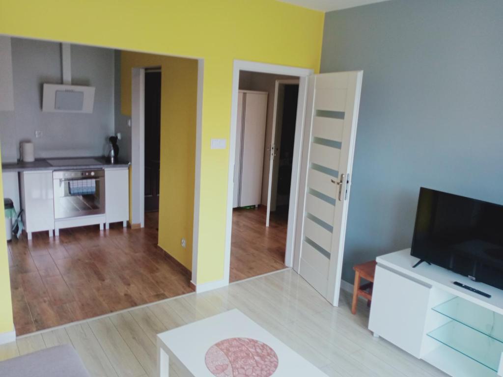 a living room with a television and a kitchen at Apartament4U - Olimpijskie Ogrody in Suwałki