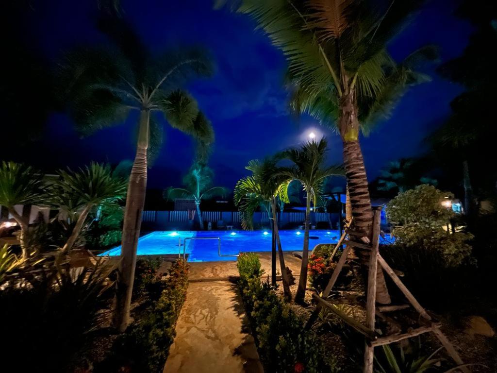 a resort pool with palm trees at night at Sunset resorts and bar in Ban Nong Chaeng