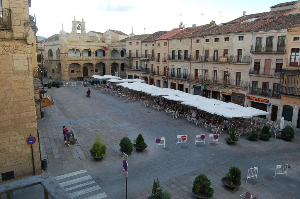 a courtyard with tables and white umbrellas in a city at Los Vetones in Ciudad-Rodrigo
