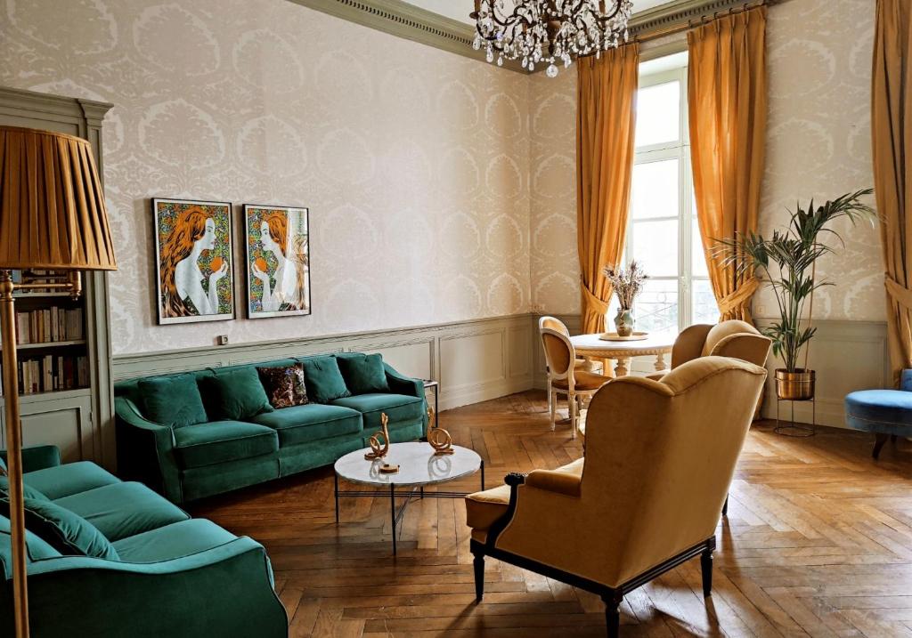 a living room with green couches and a chandelier at Le 1825, une suite luxueuse au coeur de la ville in Nantes