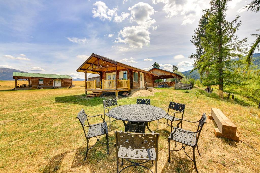 a table and chairs in front of a cabin at Cozy Farm Cabin - 9 Mi to Trout Creek! in Trout Creek