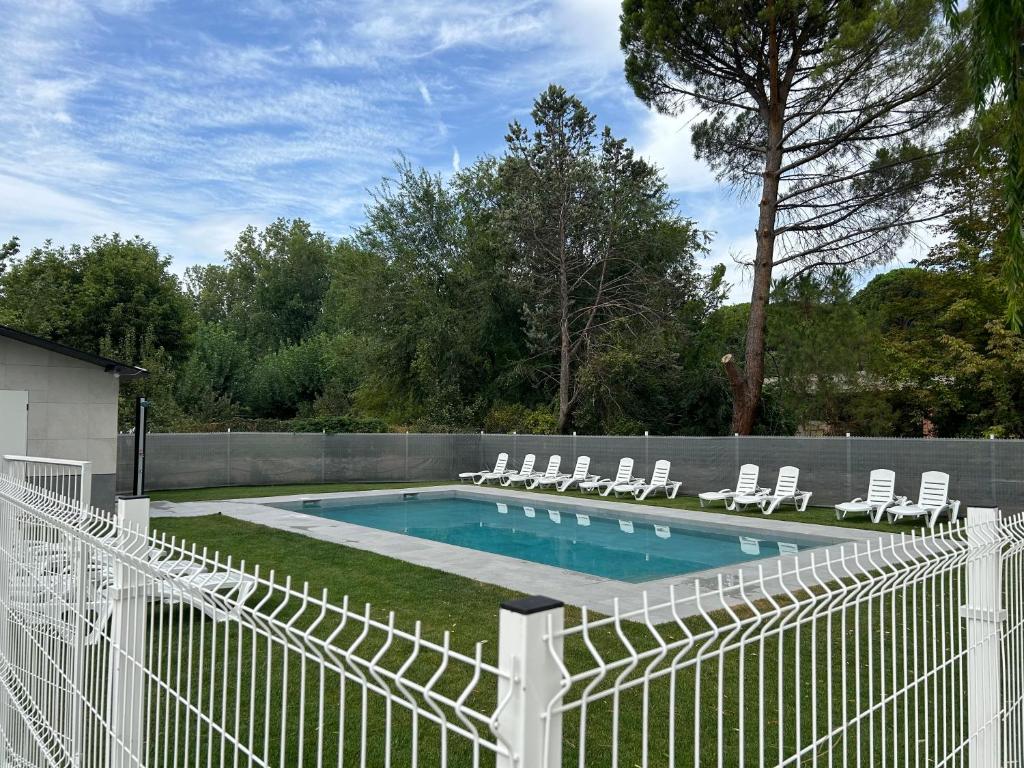 una valla blanca que rodea una piscina con tumbonas en Villa Piluca, en Pelayos de la Presa
