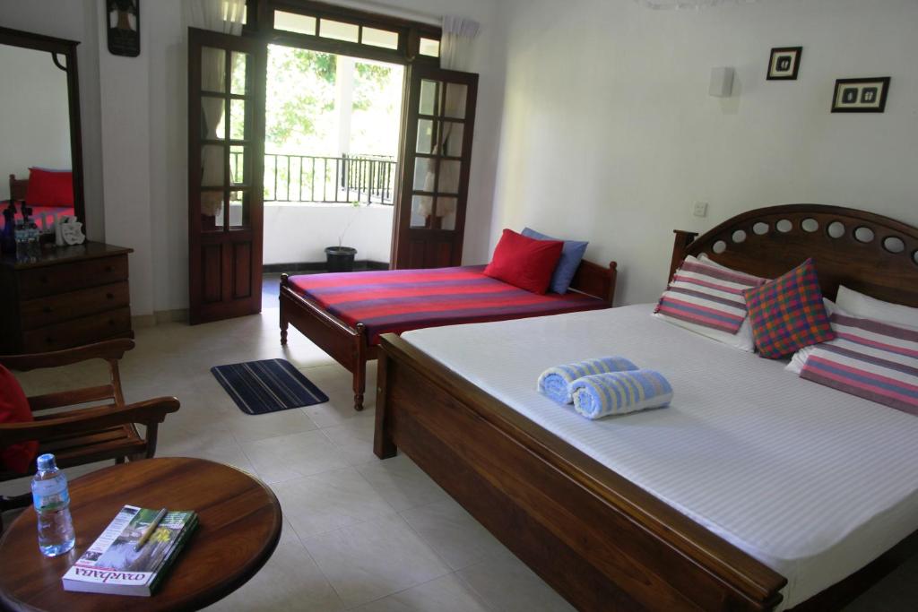 a bedroom with two beds and a table and a couch at River Side Homestay Apartment in Kandy