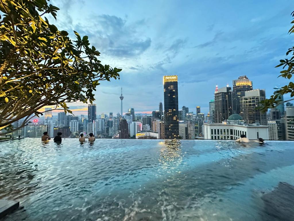 una piscina infinita con vistas al perfil urbano de fondo en The Axon Bukit Bintang By Cozy White, en Kuala Lumpur